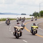 Motorcycle group on their way to New Liskeard. In the background the Presidents' Suites' Farr Island. / Groupe de moto en route vers New Liskeard. En arrière plan l'île Farr des Suites des Présidents.