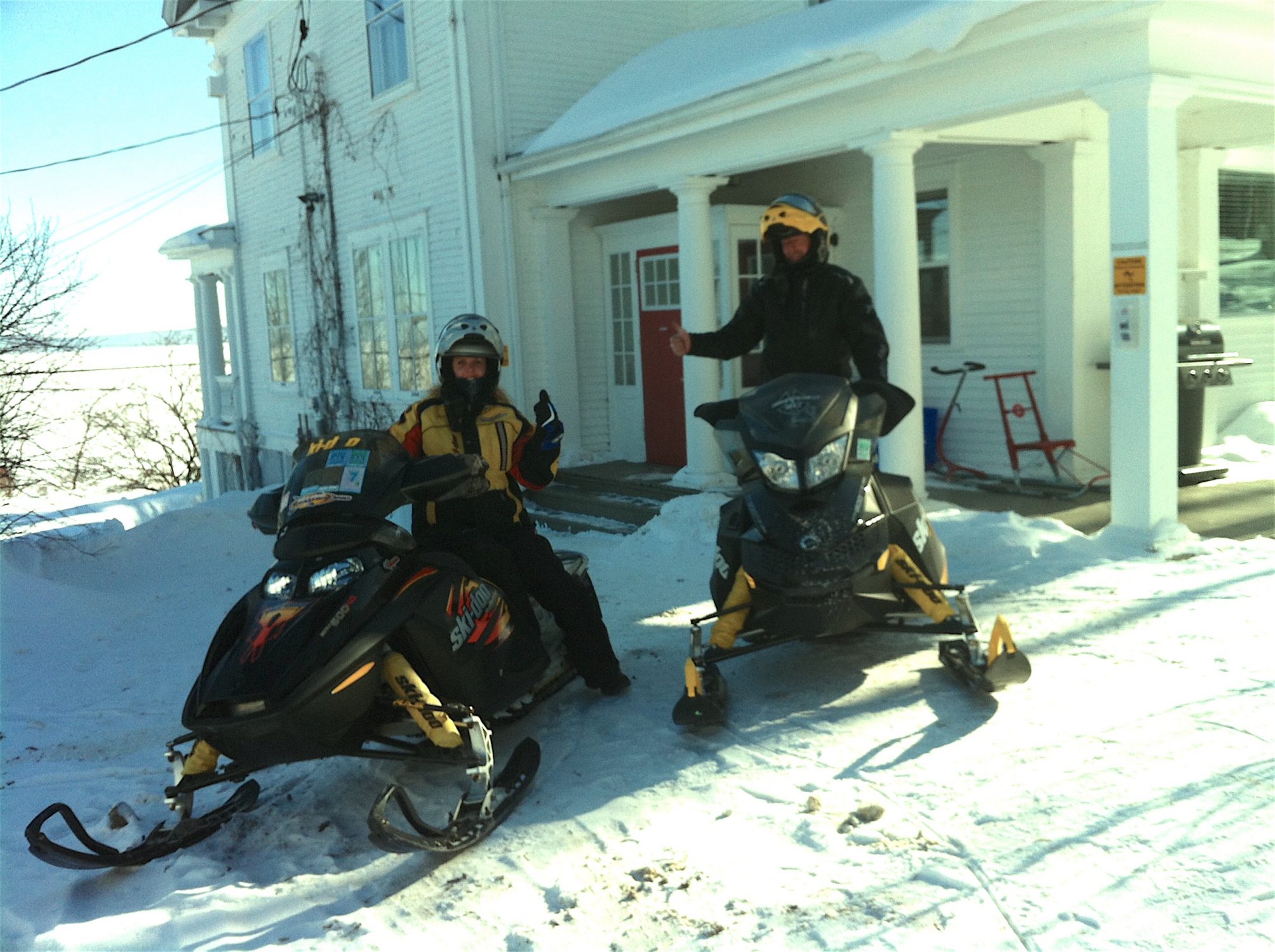 Snowmobile couple in front of the Presidents' Suites Villa. Several loops are possible from Haileybury. / Un couple en motoneige devant la Villa des Suites des Présidents. Plusieurs boucles sont possibles à partir de Temiskaming Shores.